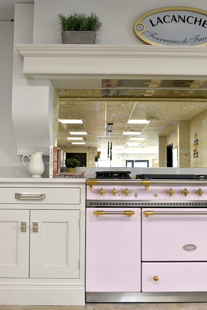 Lacanche range oven in rose pink integrated into a luxurious neutral kitchen.